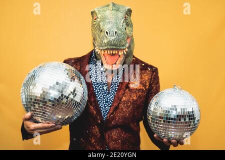Homme de mode senior portant un masque de dinosaure t-rex tout en célébrant le carnaval Vacances - concept de masquage surréaliste Banque D'Images