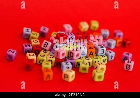 Perles de cube en bois colorées avec lettres sur fond rouge festif, mot « Love ». Saint Valentin. 14 février. Flat lay, vue de dessus. Banque D'Images