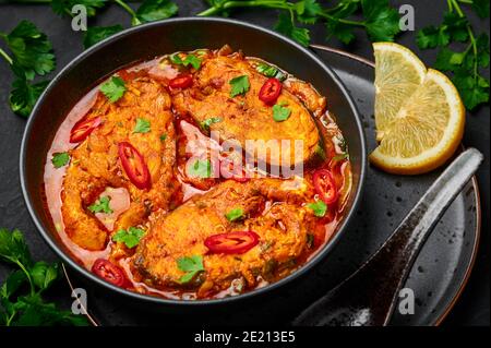 Macher Jhol dans un bol noir sur table en ardoise foncé. Cuisine indienne curry à poisson bengali. Plats et repas asiatiques. Gros plan Banque D'Images