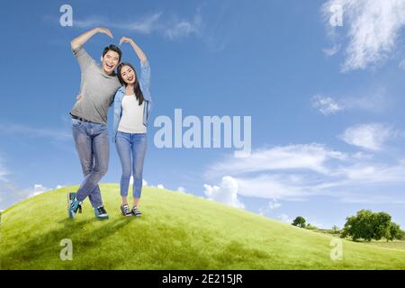 Couples asiatiques qui font la forme d'un coeur avec des mains avec un fond bleu ciel. Saint-Valentin Banque D'Images