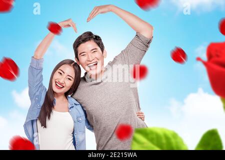 Couples asiatiques qui font la forme d'un coeur avec des mains avec un fond bleu ciel. Saint-Valentin Banque D'Images