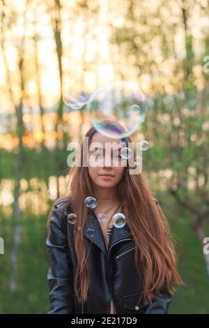 Adorable teen Girl soufflant des bulles de savon sur le terrain le jour du printemps. Banque D'Images