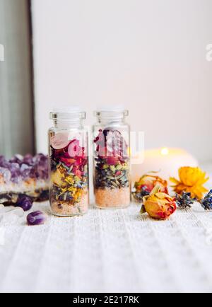 Flacons en pot à la main avec de bonnes intentions pour la protection de la maison et l'équilibre intérieur. Rempli de sel de roche himalayan, de fleurs d'herbes séchées. Banque D'Images