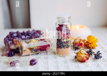 Flacons en pot à la main avec de bonnes intentions pour la protection de la maison et l'équilibre intérieur. Rempli de sel de roche himalayan, de fleurs d'herbes séchées. Banque D'Images