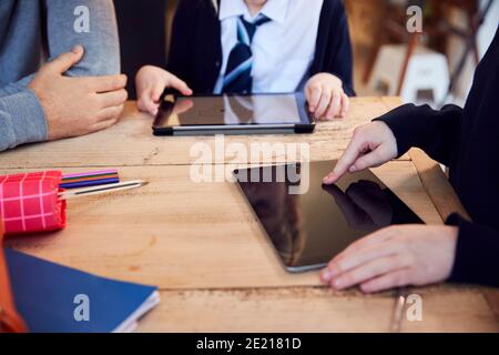 Gros plan de Père aider les enfants à porter des tablettes numériques Uniforme scolaire avec devoir Banque D'Images