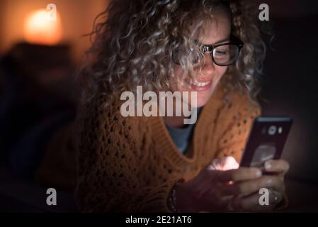 La femme adulte utilise le téléphone cellulaire Internet la nuit seule à accueil - personnes et dépendance à la technologie - connexion et concept de conférence téléphonique - s Banque D'Images