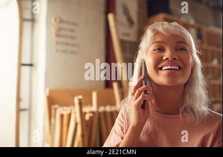 Femme propriétaire d'entreprise dans l'atelier effectuant un appel sur un téléphone mobile Banque D'Images