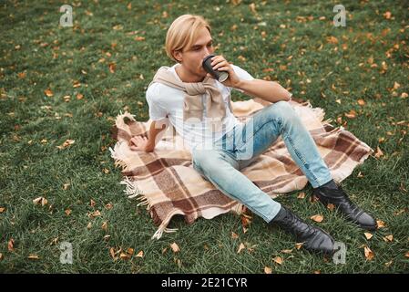 Beau homme ayant le repos à l'extérieur. Couché sur une couverture dans le parc. Banque D'Images