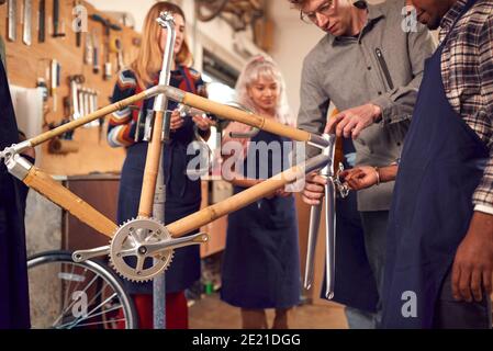 Équipe multi-culturelle dans l'atelier d'assemblage de vélo de bambou durable construit à la main Cadre Banque D'Images