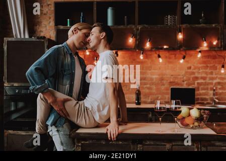 Couple gay aimant à la maison. Deux beaux hommes passionnés embrassant et embrassant en cuisine. Concept LGBT. Banque D'Images