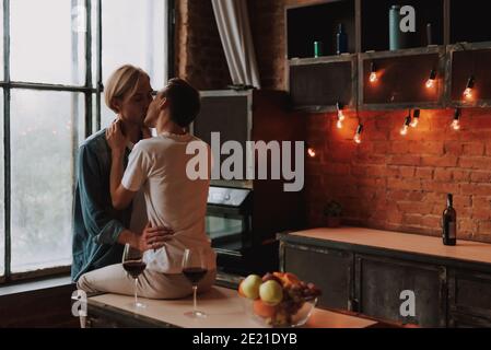 Couple gay aimant à la maison. Deux beaux hommes qui embrasent et embrassaient la cuisine. Concept LGBT. Banque D'Images