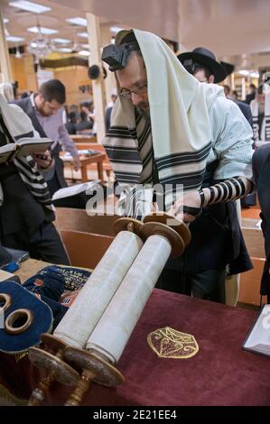 Un juif orthodoxe soulève la Torah un peu après avoir été appelé à une lecture matinale en semaine. À Crown Heights, Brooklyn. Banque D'Images