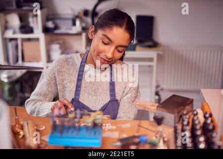 Femme Jeweler au banc travaillant sur l'anneau avec le fichier dans Studio Banque D'Images