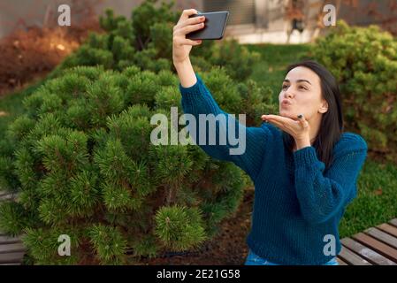 Jeune femme attirante prenant un selfie réconfortant sur un appareil photo avant de son téléphone portable Banque D'Images