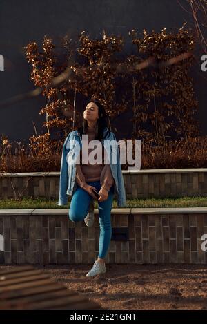 Charmante femme dans une tenue décontractée est heureux de se reposer dedans lumière du soleil du soir sur une place pittoresque Banque D'Images