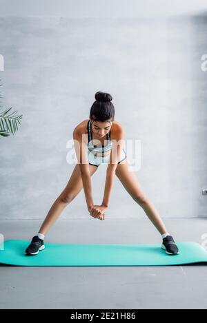 jeune sportif afro-américain faisant un exercice de virage vers l'avant sur la forme physique tapis à la maison Banque D'Images