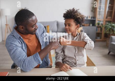 Portrait d'un père afro-américain qui s'est fait bourder de fils souriants devoirs ensemble à la maison Banque D'Images