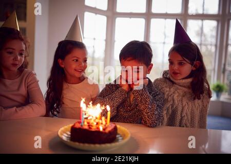 Garçon célébrant son anniversaire avec un groupe d'amis à la maison Gâteau donné décoré de Sparkler Banque D'Images