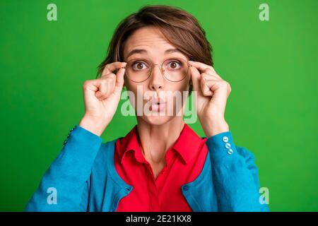 Photo de la jeune fille stupéfait surprise surprise rumeur de fausses nouvelles les mains touchent des lunettes isolées sur fond vert vif Banque D'Images