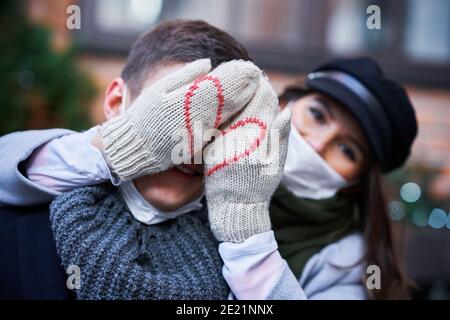 Couple heureux célébrant la Saint Valentin dans les masques pendant la pandémie de Covid-19 Banque D'Images