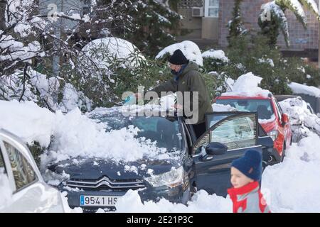 Madrid, Espagne - 10 janvier 2021 : un homme nettoie la glace et la neige de sa voiture, dans le quartier de Retiro, après la tempête, par une journée enneigée, à cause du Filo Banque D'Images