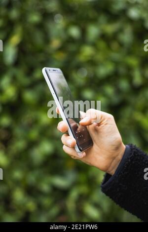 Gros plan d'une femme tenant un smartphone blanc avant de l'arrière-plan vert uni Banque D'Images