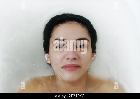 Portrait d'une belle femme brunette ayant un bain spa avec du lait. Banque D'Images
