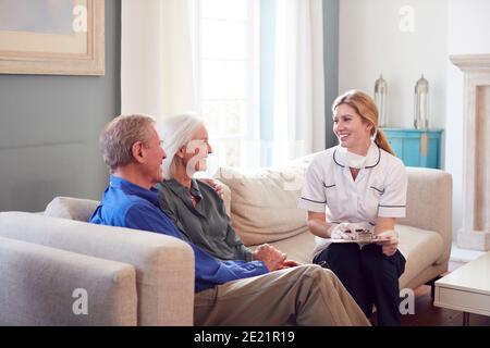 Une femme médecin avec masque rend visite à domicile à un couple senior Pour un contrôle médical pendant le verrouillage Covid-19 Banque D'Images