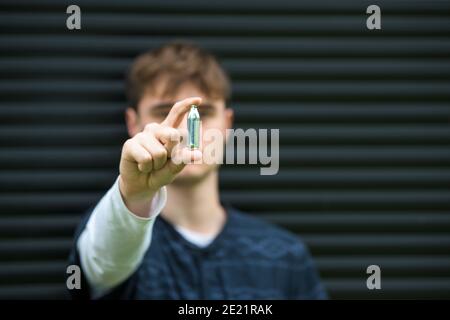 Un jeune homme montrant une cartouche d'azote, un siphon à fouetter : l'utilisation abusive de l'oxyde nitreux comme gaz riant concerne de plus en plus les organismes de santé. Ces chats Banque D'Images