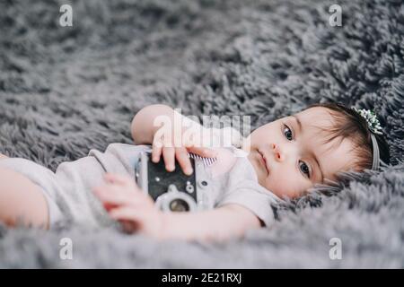 Gros plan de l'adorable et adorable bébé tenant un appareil photo reflex vintage Banque D'Images