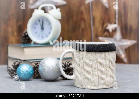 Coupe en pull en laine tricoté sur table avec livres et réveil. Composition hivernale, confort à la maison. Mise au point sélective, vue brouillard. Banque D'Images