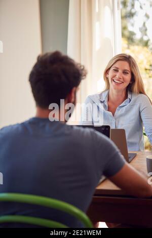 Couple avec ordinateur portable assis à la table travaillant de la maison ensemble Banque D'Images