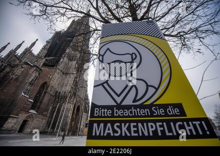 11 janvier 2021, Bade-Wurtemberg, Ulm: Un panneau en face de la cathédrale d'Ulm avec la plus haute tour de l'église dans le monde indique que les masques sont obligatoires. Photo: Stefan Puchner/dpa Banque D'Images