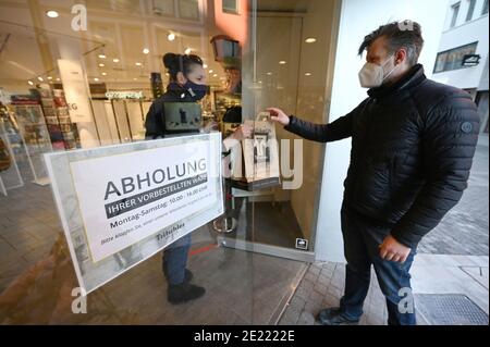 11 janvier 2021, Bade-Wurtemberg, Stuttgart: Une vendeuse remet les marchandises commandées à un client à l'entrée du magasin d'articles ménagers Tritschler. Depuis le 11 janvier, la grande majorité des entreprises du sud-ouest sont de nouveau autorisées à faire collecter leurs marchandises sur place par des clients si leurs commandes ont déjà été passées par téléphone ou en ligne, par exemple. Photo: Marijan Murat/dpa Banque D'Images