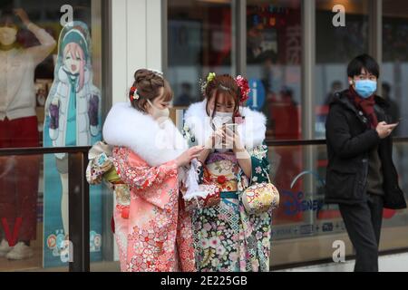 Les femmes portant des kimono et des masques qui passent du temps à Shibuya Crossing pendant la journée « Coming of Age » en Tokyo.Coming de la Journée de l'âge célèbre ceux qui ont atteint l'âge de 20 ans. C'est un jour férié le deuxième lundi de janvier au Japon. Cependant, à la lumière du taux croissant d'infection par COVID19 au Japon, le jour de l'âge de 2021 n'était pas le même comme d'habitude. La cérémonie officielle n'était en ligne que dans la plupart des bureaux de la ville au Japon. Dans la place populaire Shibuya Crossing n'était que peu de filles dans le magnifique kimono. Toutes les personnes portant un masque. Banque D'Images
