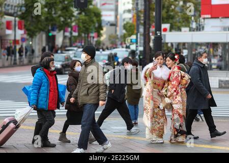 Les femmes vêtues de kimono prennent des photos à Shibuya Crossing pendant le jour de 'Coming of Age' en Tokyo.Coming du jour de l'âge célèbre ceux qui ont 20 ans. C'est un jour férié le deuxième lundi de janvier au Japon. Cependant, à la lumière du taux croissant d'infection par COVID19 au Japon, le jour de l'âge de 2021 n'était pas le même comme d'habitude. La cérémonie officielle n'était en ligne que dans la plupart des bureaux de la ville au Japon. Dans la place populaire Shibuya Crossing n'était que peu de filles dans le magnifique kimono. Toutes les personnes portant un masque. Banque D'Images