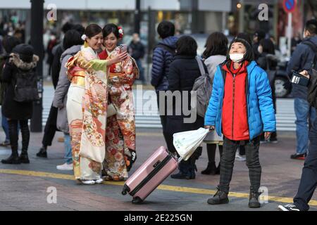 Les femmes vêtues de kimono prennent des photos à Shibuya Crossing pendant le jour de 'Coming of Age' en Tokyo.Coming du jour de l'âge célèbre ceux qui ont 20 ans. C'est un jour férié le deuxième lundi de janvier au Japon. Cependant, à la lumière du taux croissant d'infection par COVID19 au Japon, le jour de l'âge de 2021 n'était pas le même comme d'habitude. La cérémonie officielle n'était en ligne que dans la plupart des bureaux de la ville au Japon. Dans la place populaire Shibuya Crossing n'était que peu de filles dans le magnifique kimono. Toutes les personnes portant un masque. Banque D'Images