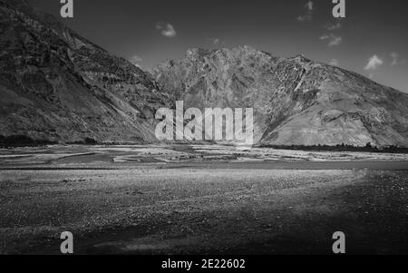 Le lit et la vallée de Spiti flanqués de hauts sommets et de ridgeline des montagnes de l'Himalaya sous le ciel bleu en été près de Kaza, Himachal Pradesh, Inde. Banque D'Images