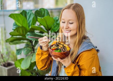 Femme mangeant le bol de poke biologique cru avec du riz et des légumes gros plan sur la table. Vue de dessus horizontale Banque D'Images