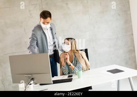 Les jeunes travailleurs d'affaires portent des masques pour les protéger et prendre soin de vous de leur santé en travaillant sur un ordinateur Banque D'Images