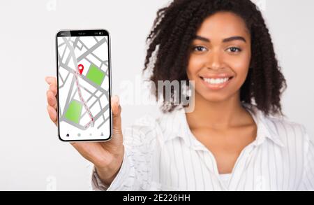 Black Lady tenant un smartphone avec des cartes en ligne de navigation GPS ouvertes À l'écran Banque D'Images