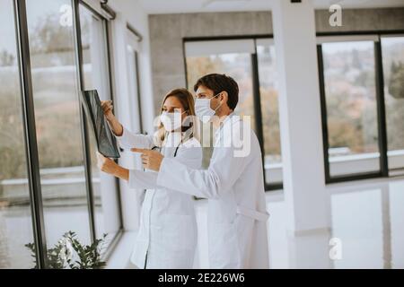 Équipe de médecins avec masques protecteurs pour le visage examinant la radiographie dans le bureau Banque D'Images
