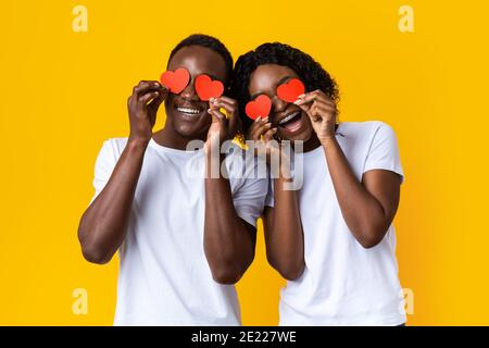 Jeune couple noir tenant le cœur d'amour rouge sur les yeux Banque D'Images