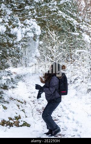 Jeune fille enlevant la neige des arbres. Femme adulte jouant avec la neige Banque D'Images