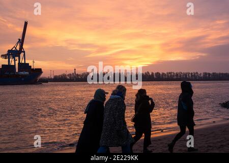 Hambourg, Allemagne. 10 janvier 2021. Les gens sont sur la plage de l'Elbe au coucher du soleil. Le beau temps a attiré de nombreuses personnes à la plage d'Elbe à Hambourg-Övelgönne le dimanche. Crédit : Bodo Marks/dpa/Alay Live News Banque D'Images