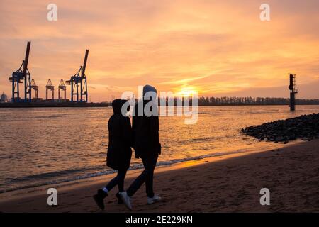 Hambourg, Allemagne. 10 janvier 2021. Les gens sont sur la plage de l'Elbe au coucher du soleil. Le beau temps a attiré de nombreuses personnes à la plage d'Elbe à Hambourg-Övelgönne le dimanche. Crédit : Bodo Marks/dpa/Alay Live News Banque D'Images