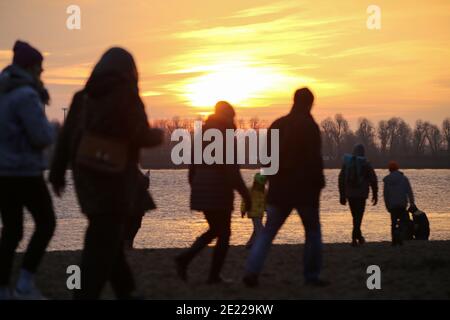 Hambourg, Allemagne. 10 janvier 2021. Les gens sont sur la plage de l'Elbe au coucher du soleil. Le beau temps a attiré de nombreuses personnes à la plage d'Elbe à Hambourg-Övelgönne le dimanche. Crédit : Bodo Marks/dpa/Alay Live News Banque D'Images