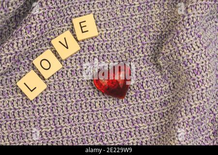 Saint-Valentin composition simple sur fond tricoté, mot d'amour et coeur rouge. Photo de haute qualité Banque D'Images