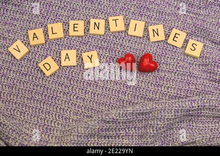 Inscription du mot de la Saint-Valentin avec deux coeurs rouges sur fond de chandails tricotés, espace de texte Banque D'Images