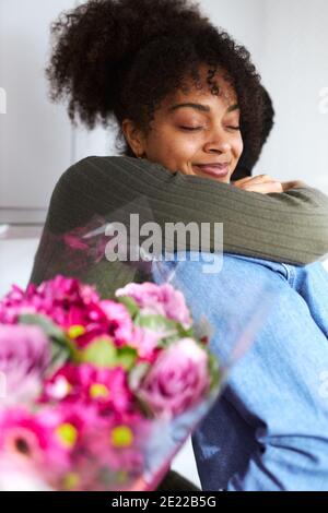 Couple romantique à la maison avec homme Femme surprenante avec Bunch De fleurs célébrant la Saint Valentin Banque D'Images